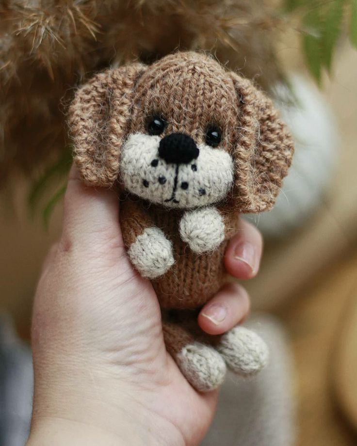 a person holding a small stuffed dog in their hand