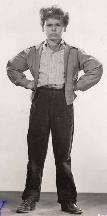 an old black and white photo of a young man in suspenders standing with his hands on his hips