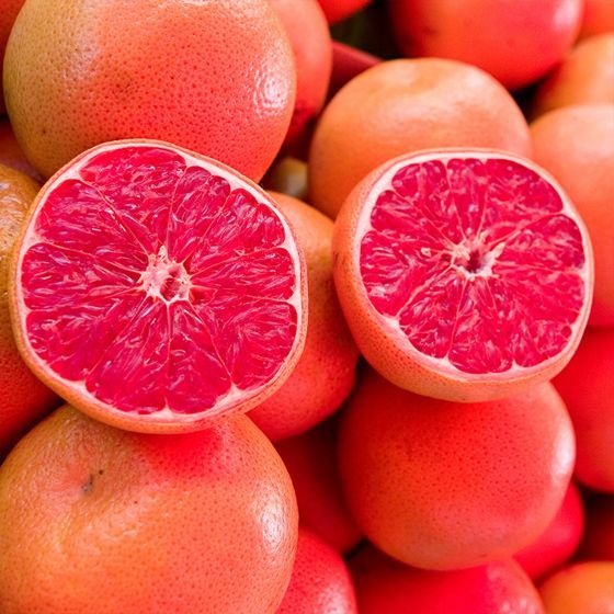 a pile of grapefruits with one cut in half