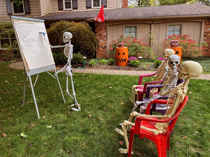 skeleton lawn decorations in front of a house with a dry erase board on the lawn