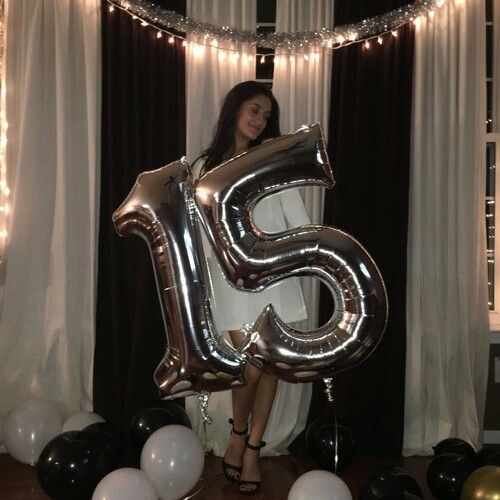 a woman standing in front of balloons with the number five