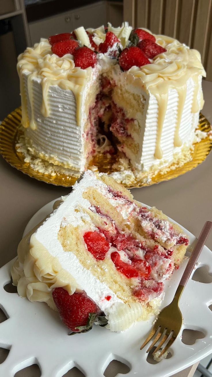 two pieces of cake with strawberries on top and one slice missing from the cake