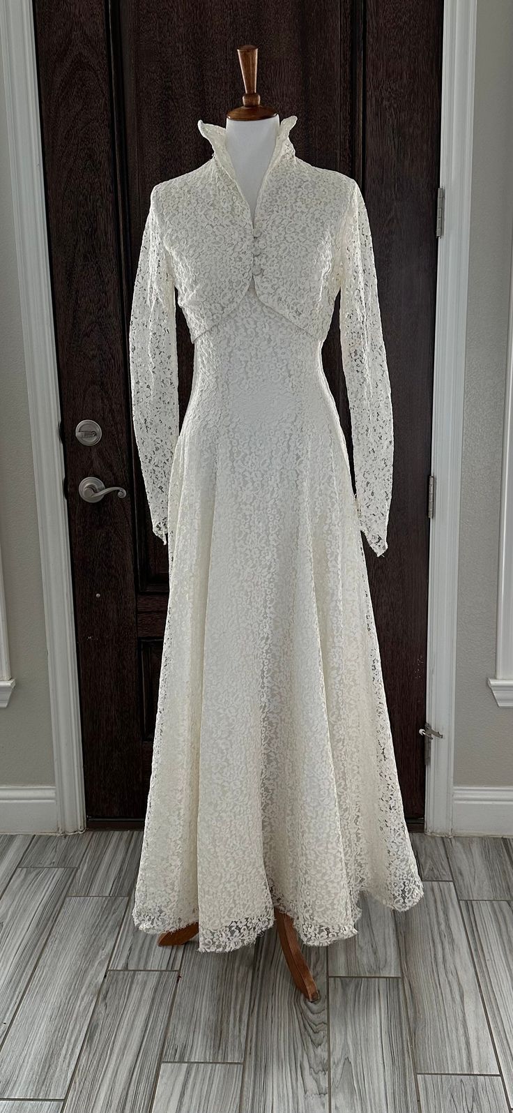 a white dress on a mannequin in front of a door with wooden floors