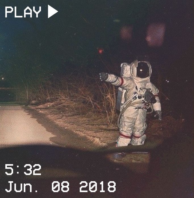 an astronaut walking down a road at night