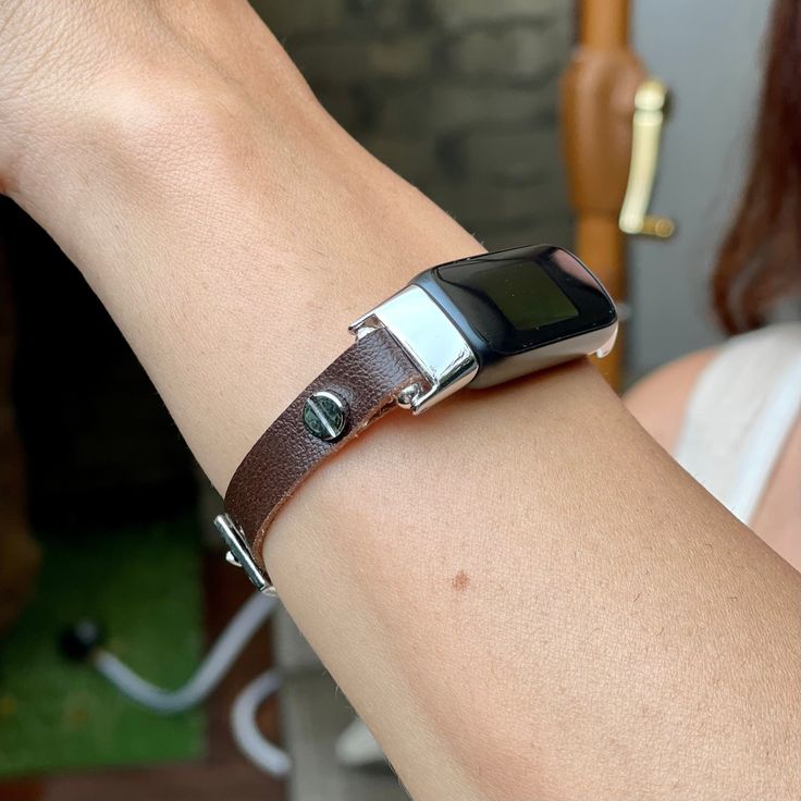 a close up of a person wearing a smart watch on their arm with a leather band