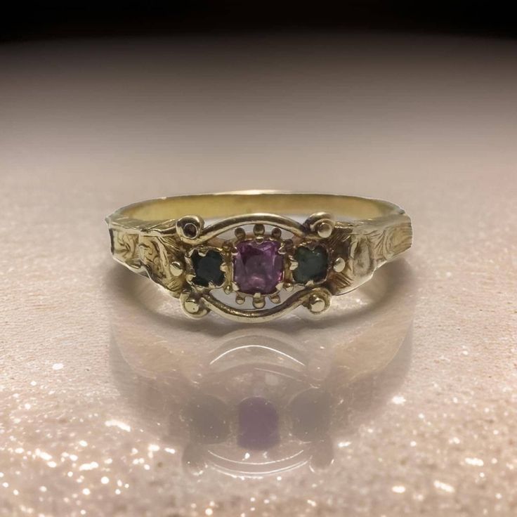 Immerse yourself in the grandeur of the Victorian era with this exceptional antique ring, a treasure from the mid-19th century (tests thereabouts). Crafted with precision, this ring is made from solid 18 carat gold, tested to near perfection, and exudes a timeless elegance that is both rare and captivating. At the heart of this royal piece lies a luminous, foiled natural ruby, its vibrant red hue symbolizing passion and nobility. This stunning gemstone is gracefully flanked by two natural emeral Green And Gold Promise Ring, Unique Vintage Engagement Rings Antiques, Vintage Stone Ring, Vintage Floral Ring, Heirloom Rings Vintage, Vintage Wedding Rings Antique Silver, Ceremonial Yellow Gold Emerald Heirloom Ring, Ceremonial Heirloom Yellow Gold Emerald Ring, Gold Emerald Heirloom Ring With Intricate Design