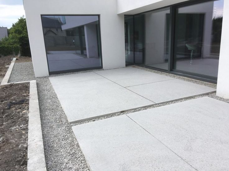 an empty patio in front of a white building with glass doors and gravel area on the ground