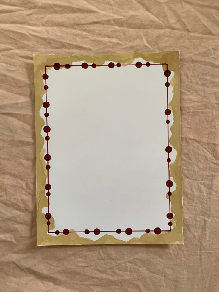 a square shaped mirror sitting on top of a bed covered in brown and white sheets