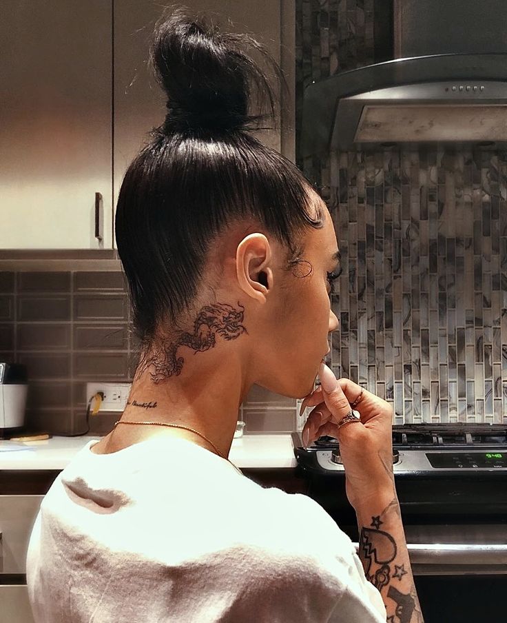 a woman with tattoos on her neck is brushing her teeth in front of an oven