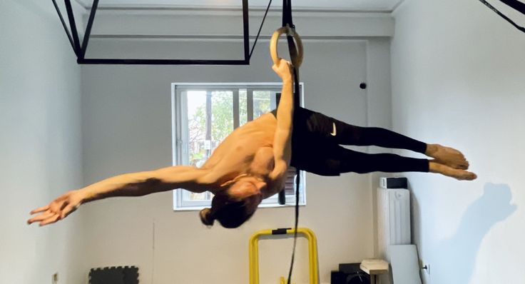 a man hanging upside down on a rope in a room with other equipment and tools