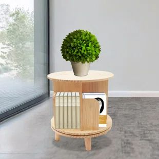 a round wooden table with a potted plant on top and books in the middle