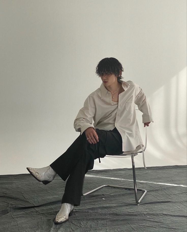 a person sitting on a chair in front of a white wall and wearing black pants