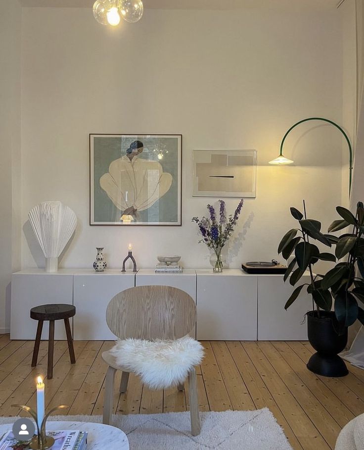 a living room filled with furniture and a painting hanging on the wall next to a window