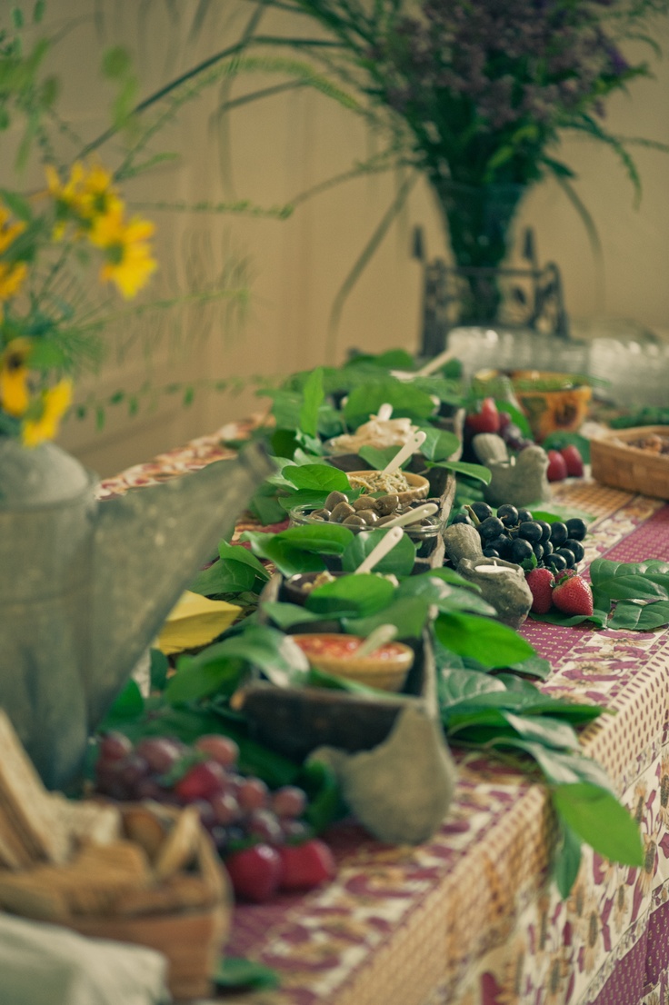 a table topped with lots of different types of fruit and veggies next to a vase filled with flowers