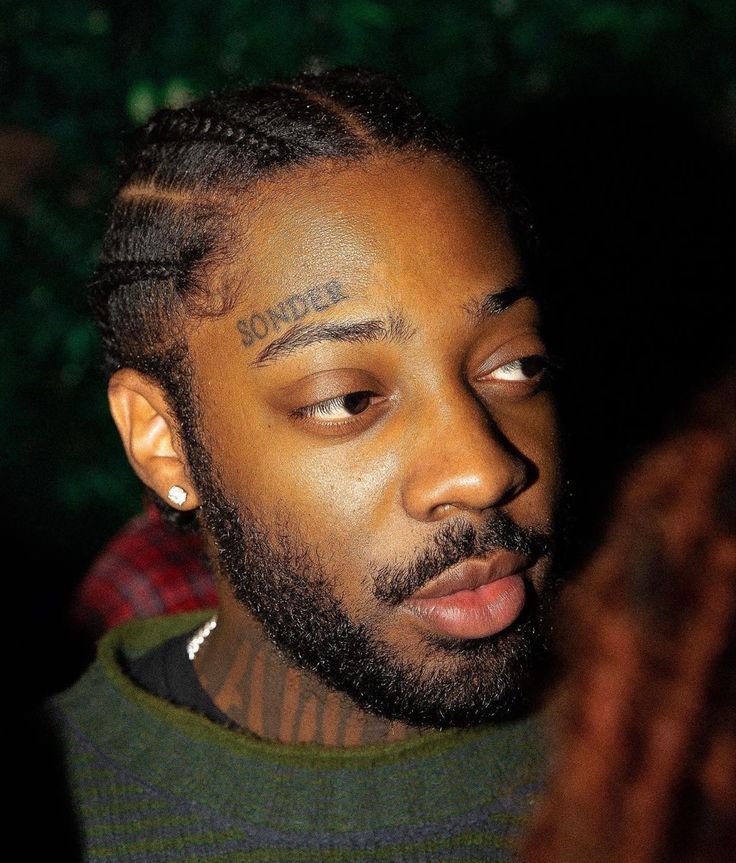 a close up of a person with tattoos on his face and hair in dreadlocks