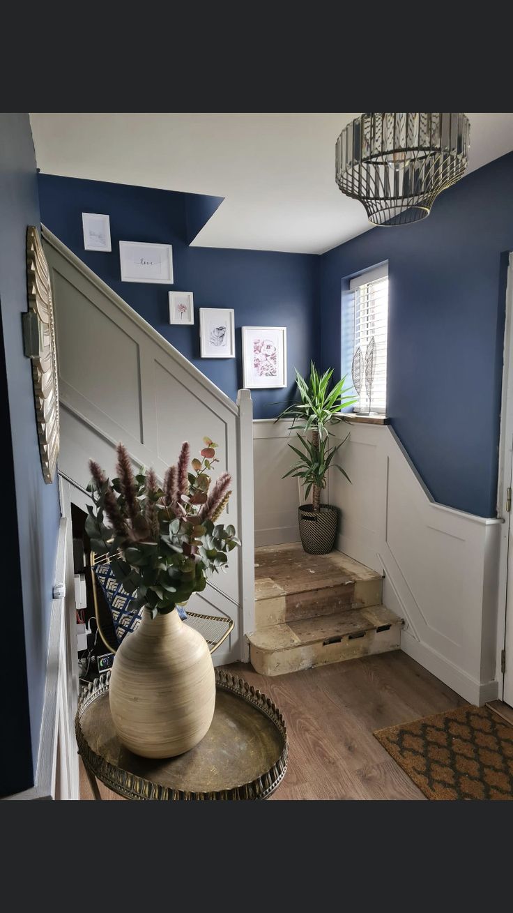 a vase filled with flowers sitting on top of a wooden table next to a stair case