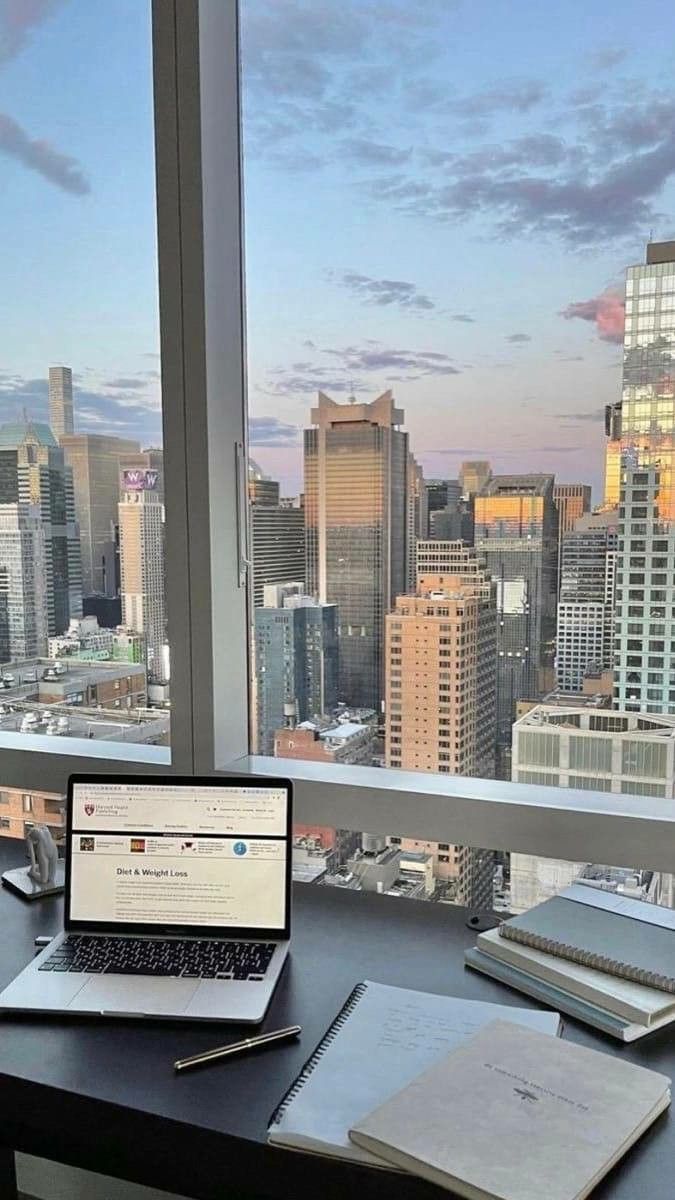 an open laptop computer sitting on top of a desk in front of a large window