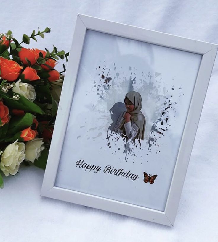 a white frame with an image of a woman on it next to flowers and a bouquet