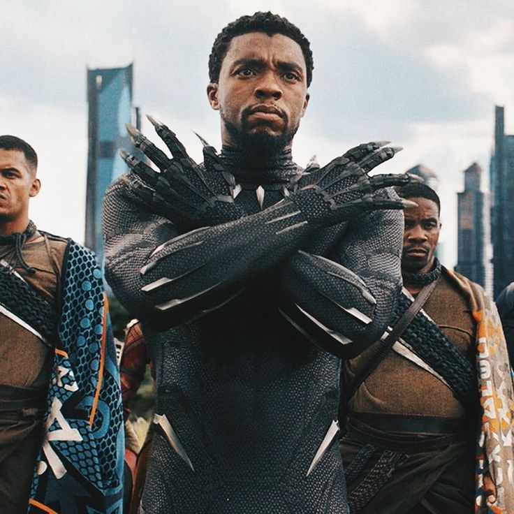 the black panther is standing in front of other men with their hands on their chest