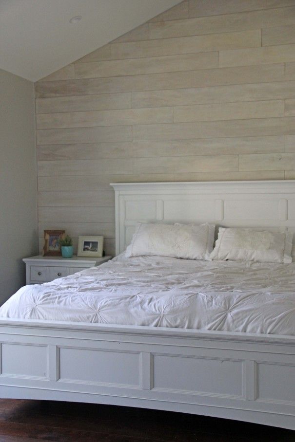 a large white bed sitting in a bedroom next to a wooden headboard and foot board