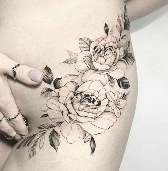 a woman's stomach with flowers and leaves tattooed on the side by her hand