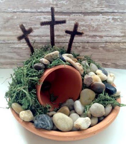 a bowl filled with rocks and grass next to two crosses