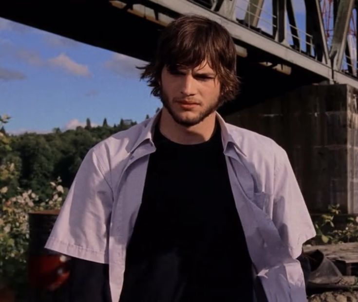 a young man standing in front of a bridge