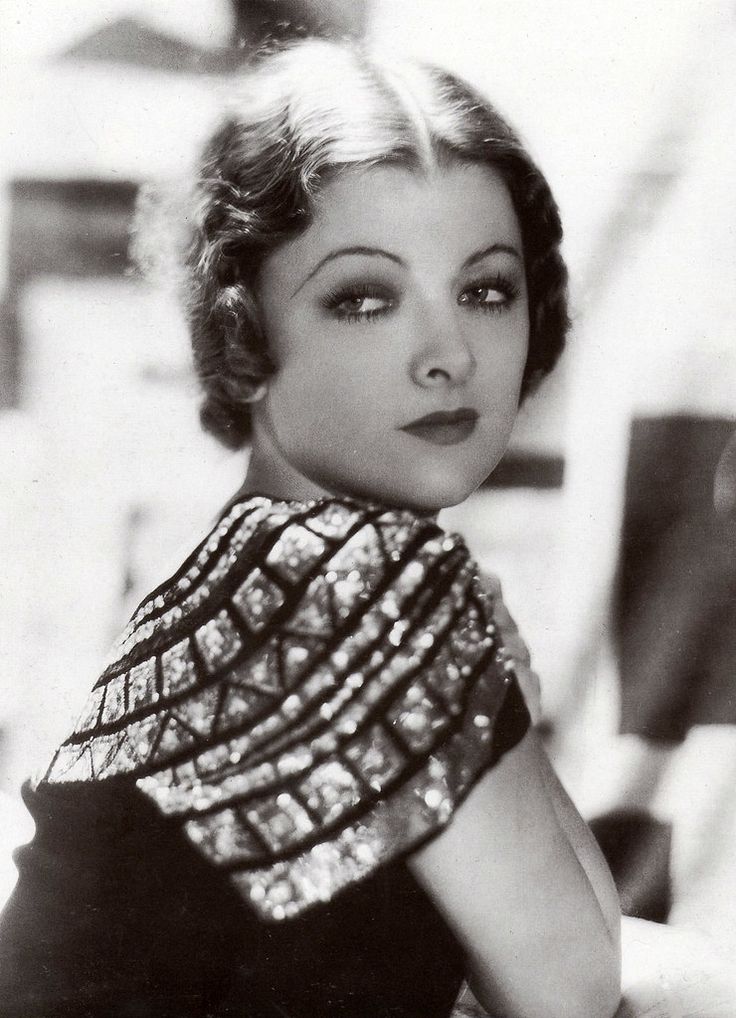 an old black and white photo of a woman with short hair wearing a beaded dress