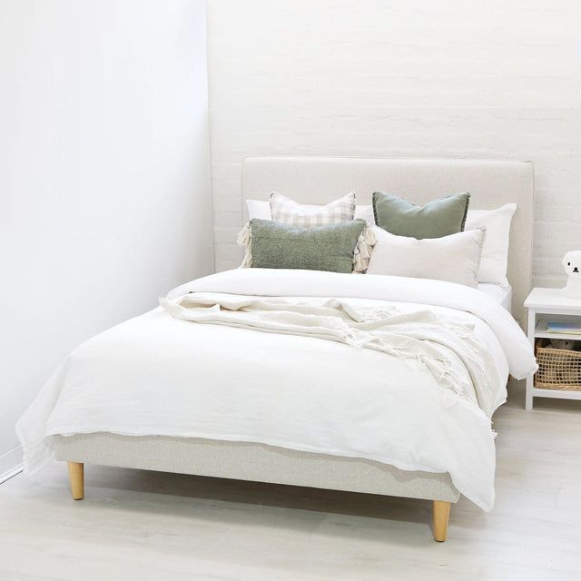 a bed with white sheets and pillows in a room