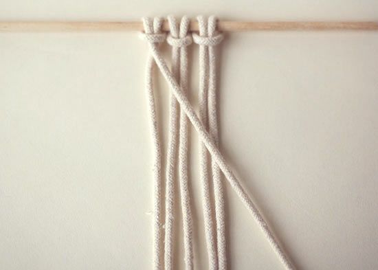 several white ropes are hanging on a wooden stick in front of a wall mounted clock