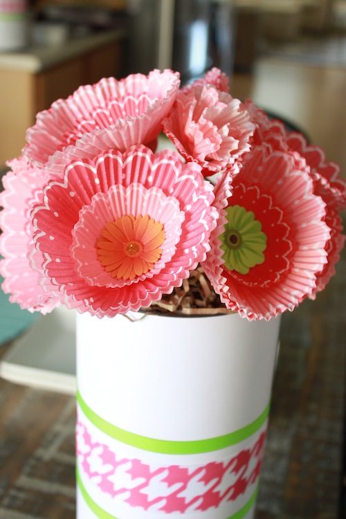 pink flowers in white vases with green trim and paper fans attached to the stems