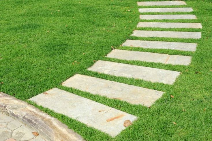 a stone path in the middle of a grassy field