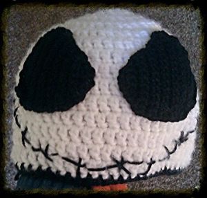 a crocheted jack skellingy hat with black eyes and nose is shown