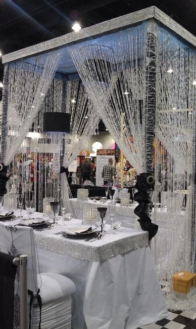 the table is set up for an event with white linens and crystal beading