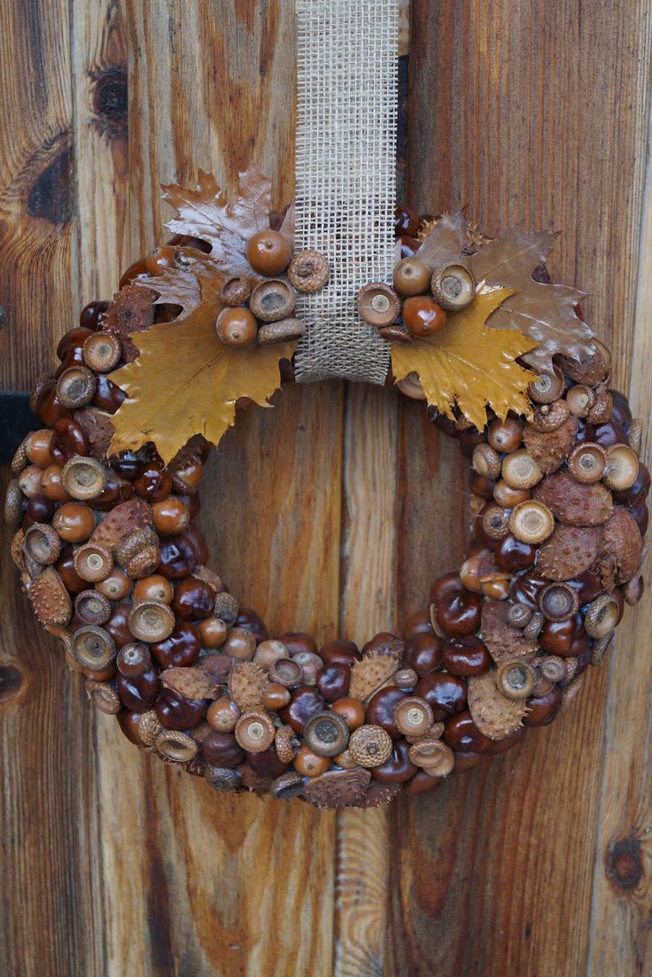 a wreath made out of acorns and leaves on a wooden door with burlocks