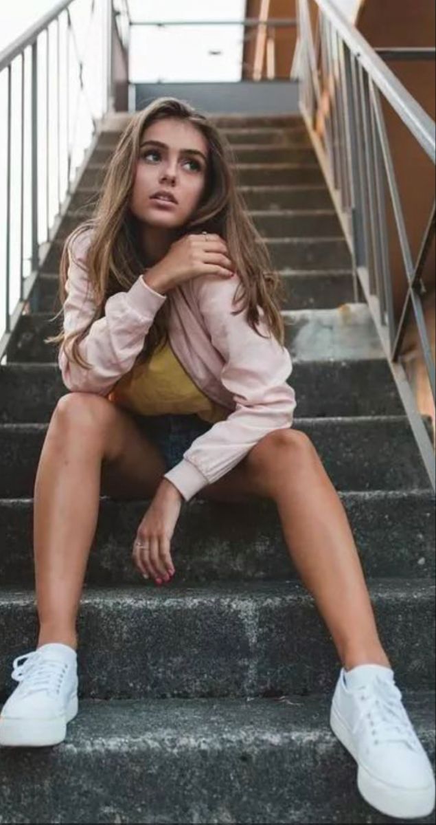 a beautiful young woman sitting on some stairs