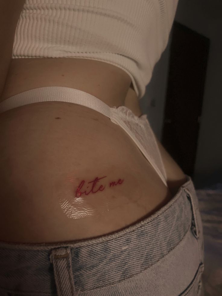 a woman's stomach with the word bite me written on her left side belly