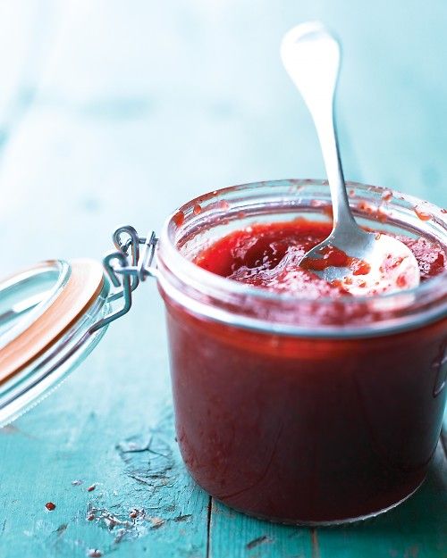 a glass jar filled with liquid sitting on top of a table next to a spoon