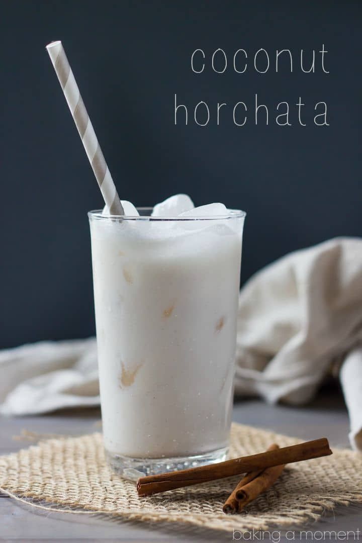 a glass filled with coconut horchata sitting on top of a table next to cinnamon sticks