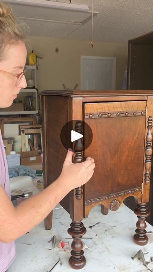 a woman is working on an old cabinet