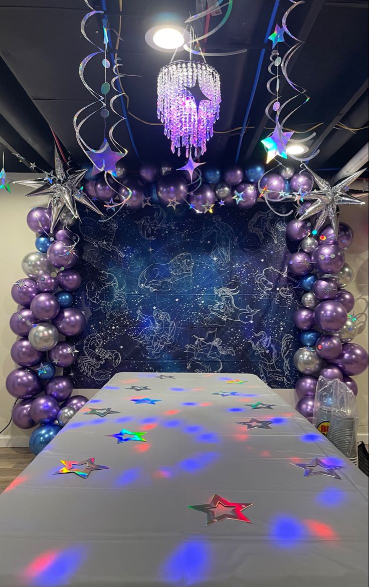 a table covered in purple and silver balloons