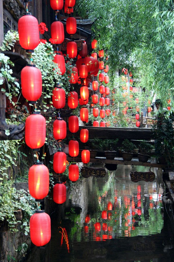 many red lanterns hanging from the side of a bridge