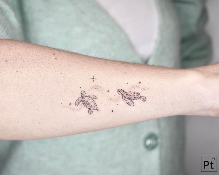 a woman's arm with two small turtles on the left side of her arm