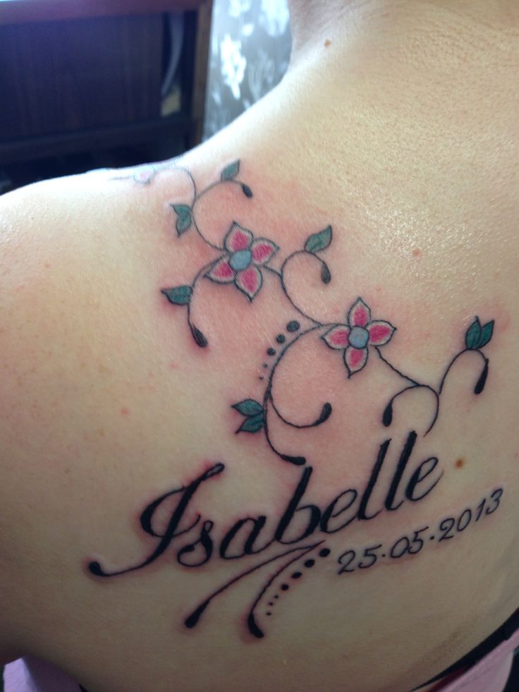 the back of a woman's shoulder with a name and flowers tattoo on it