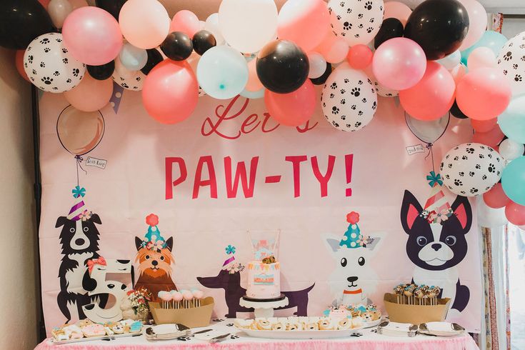 a birthday party with balloons, cake and cupcakes on a table in front of a sign that says let's paw - ty