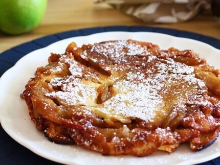 an apple pie on a white plate with powdered sugar