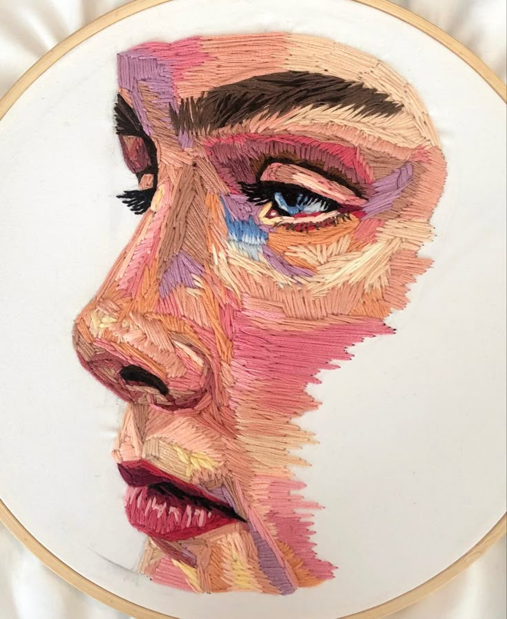 a woman's face is made out of colored threads on a white plate