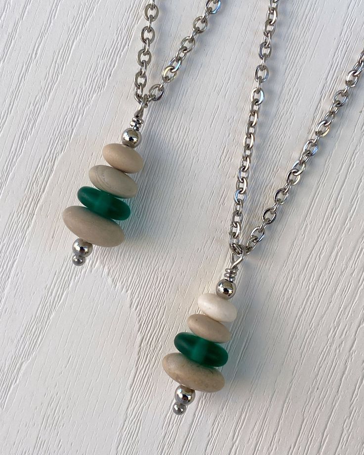 Cairns have long been used to mark trails and paths so that we don’t lose our way in the wilderness. Take a little bit of the trail with you wherever you go with this dainty cairn necklace. Three hand drilled pebbles and a heishi glass bead are hung on small stainless steel chain. Comfortable and easy to wear. Stainless steel chain and findings won’t tarnish, and won’t irritate sensitive skin. -Stainless steel findings and chain -Hand drilled natural beach pebbles and a green glass heishi bead - Cairn Necklace, Beach Pebbles, Green Flats, Rock Jewelry, Heishi Beads, Cairns, Sea Glass Jewelry, The Wilderness, Steel Chain