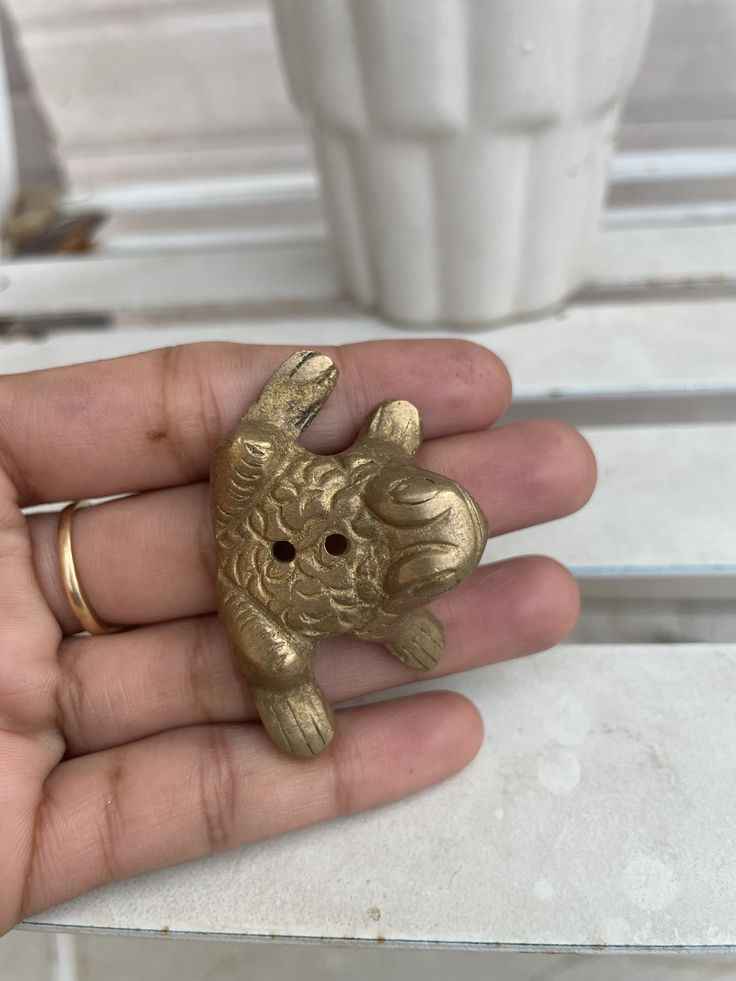 a person is holding a gold elephant ring