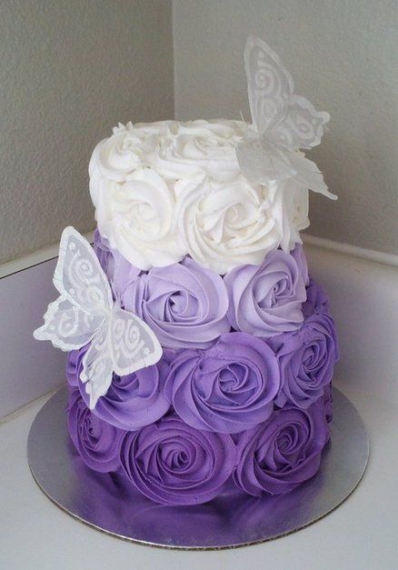 there is a purple and white cake with roses on it that have butterflies on top